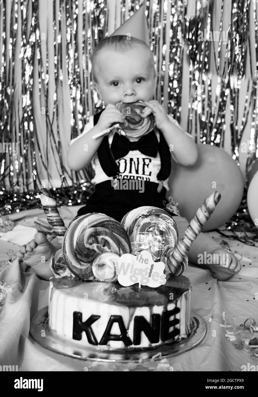 Wiggles Cake Smash Photography Session mit niedlichem Baby, der eins wird. Seinen ersten Geburtstag feiern Stockfoto