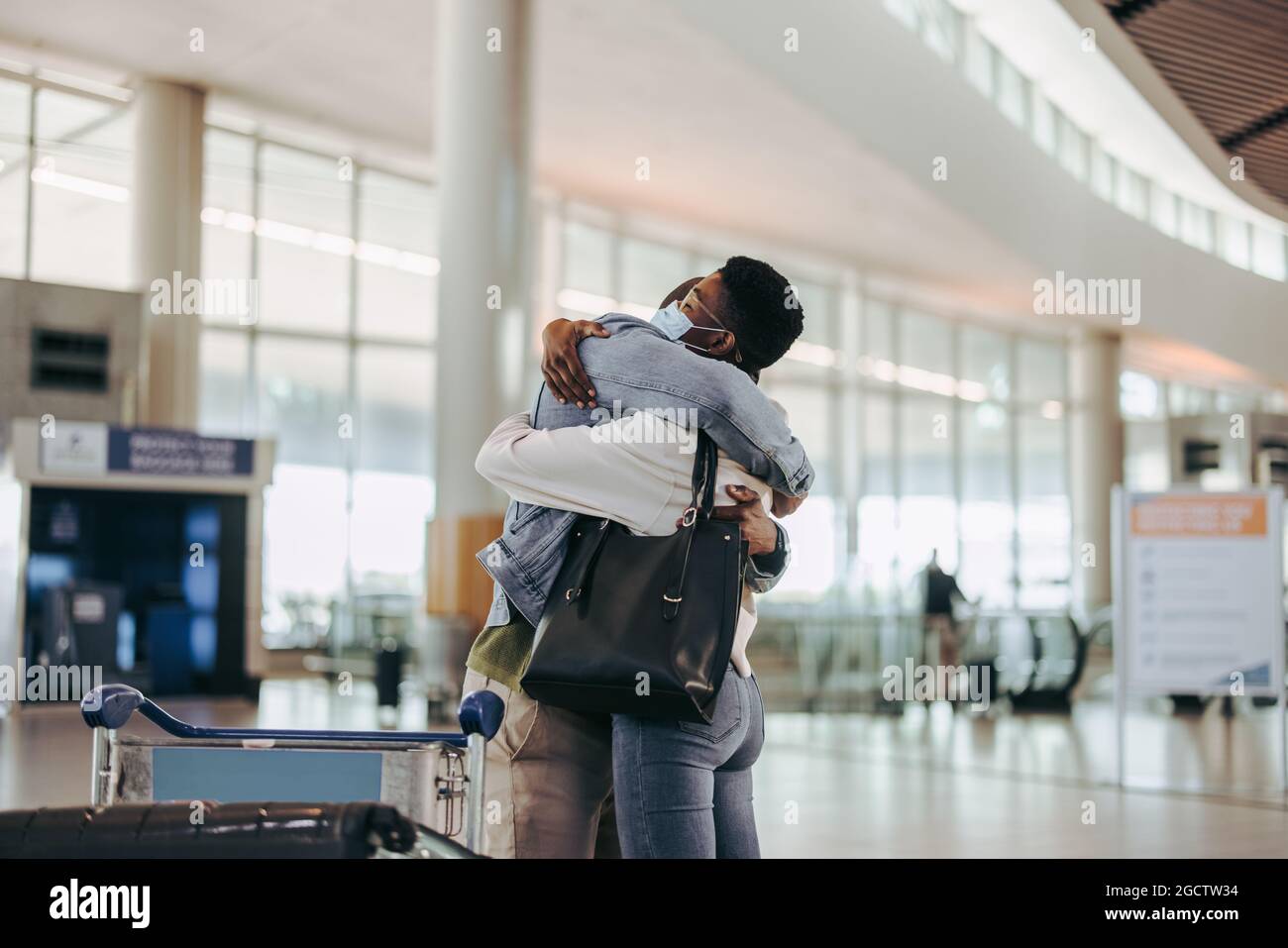 Das Paar umarmt sich vor dem Abflug am Flughafen. Die Frau umarmte ihren Mann am Abflugsteig des Flughafens. Stockfoto