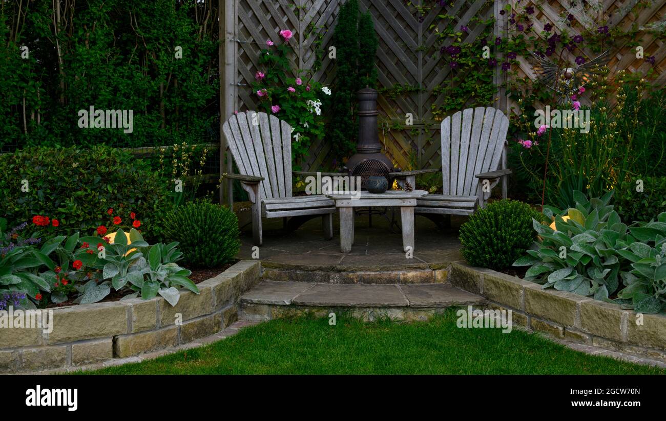 Wunderschöner, farbenprächtiger Garten (modernes Design, geschwungene Wände, dekorative Chiminea, Terrassen, Lichter in der Abenddämmerung) - Yorkshire England Großbritannien Stockfoto