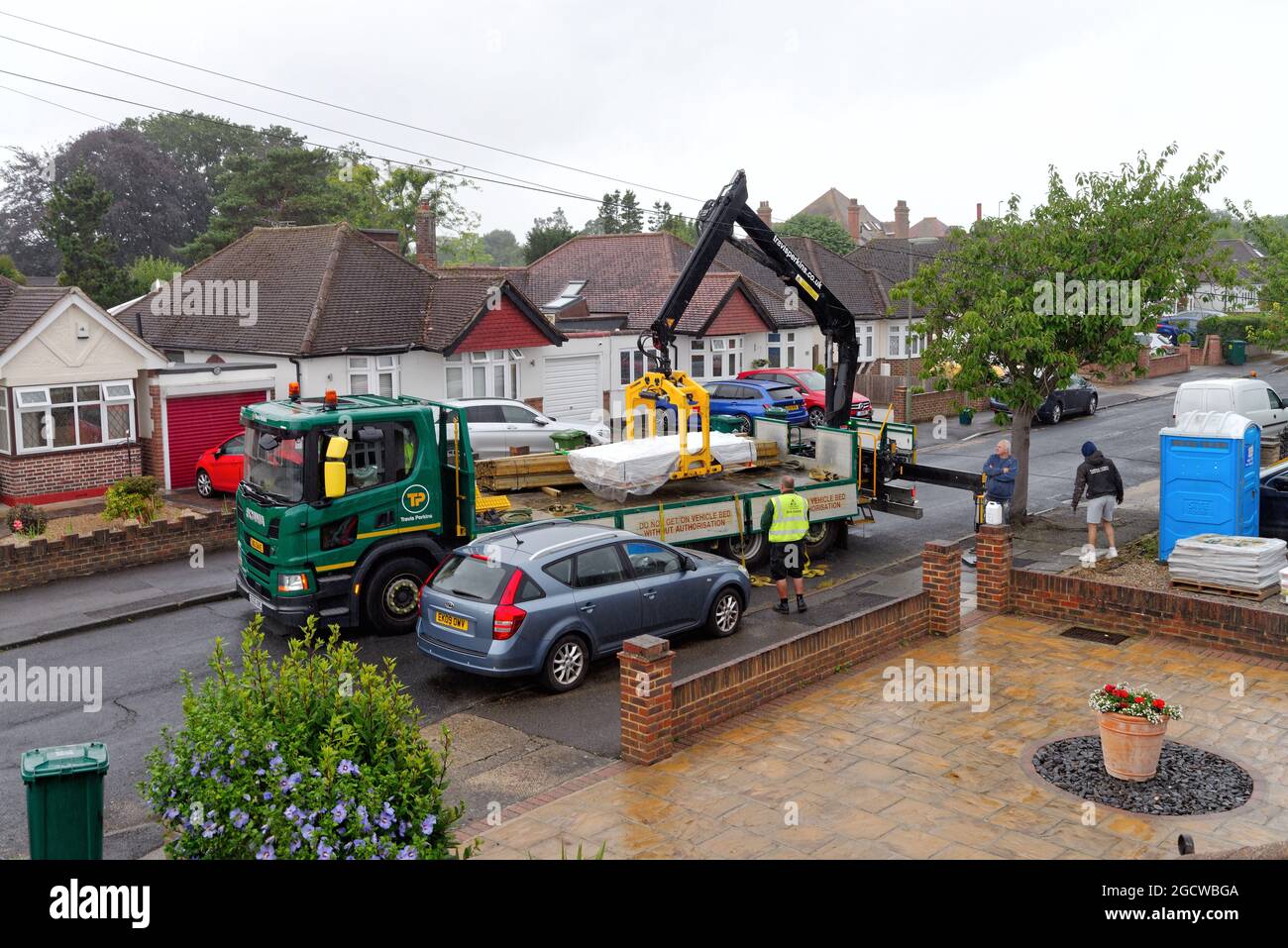 Ein Travis Perkins-Tieflader liefert Baumaterialien zu einem Vorstadthaus in Shepperton, Surrey, England Stockfoto