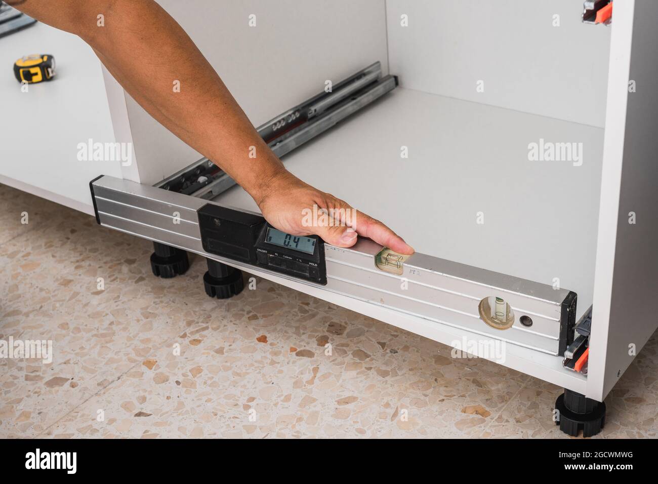 Mann mit einer Wasserwaage, um die Installation der Möbel zu überprüfen Stockfoto