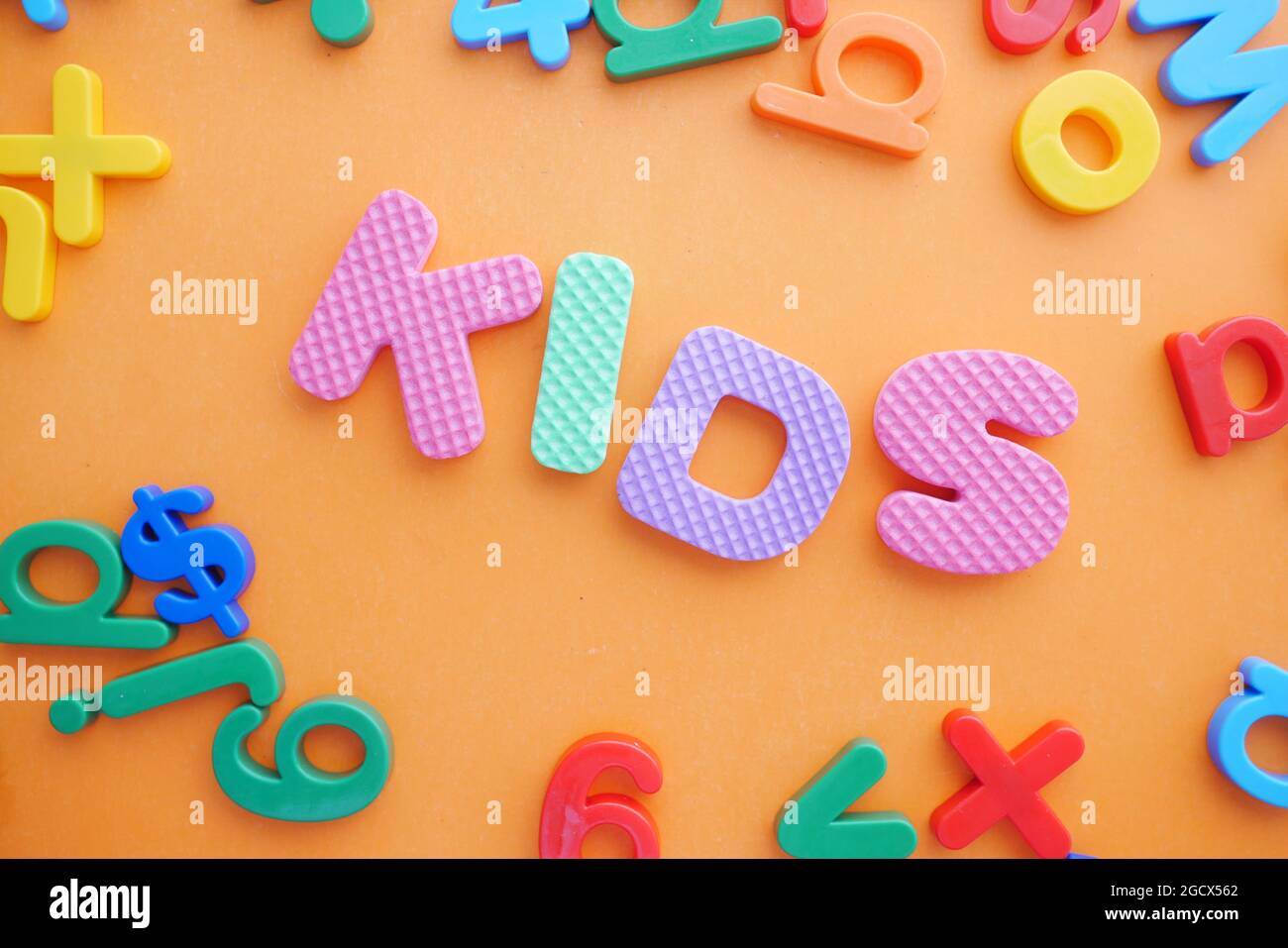 Bunte Plastikbuchstaben auf orangefarbenem Hintergrund, Draufsicht Stockfoto