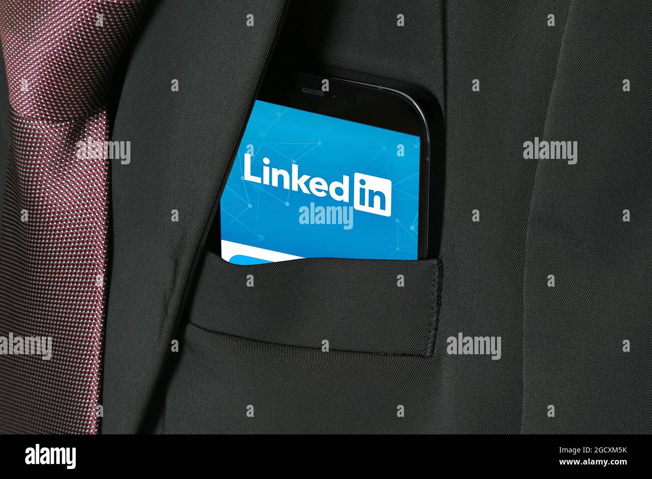 LinkedIn auf dem Mobiltelefon. Professionelles Networking, blaues Logo auf dem Smartphone-Bildschirm. Online-Jobsuche und Jobangebote in App. Business-Anzugtasche. Stockfoto