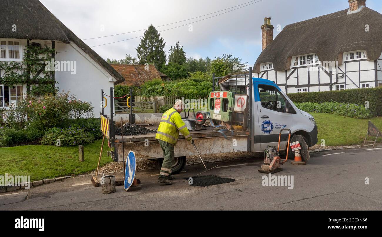 Hampshire, England, Großbritannien. 2021. Mitarbeiter des Wasserunternehmens repariert die Straßenoberfläche nach dem Füllen eines Lochs im Asphalt Stockfoto