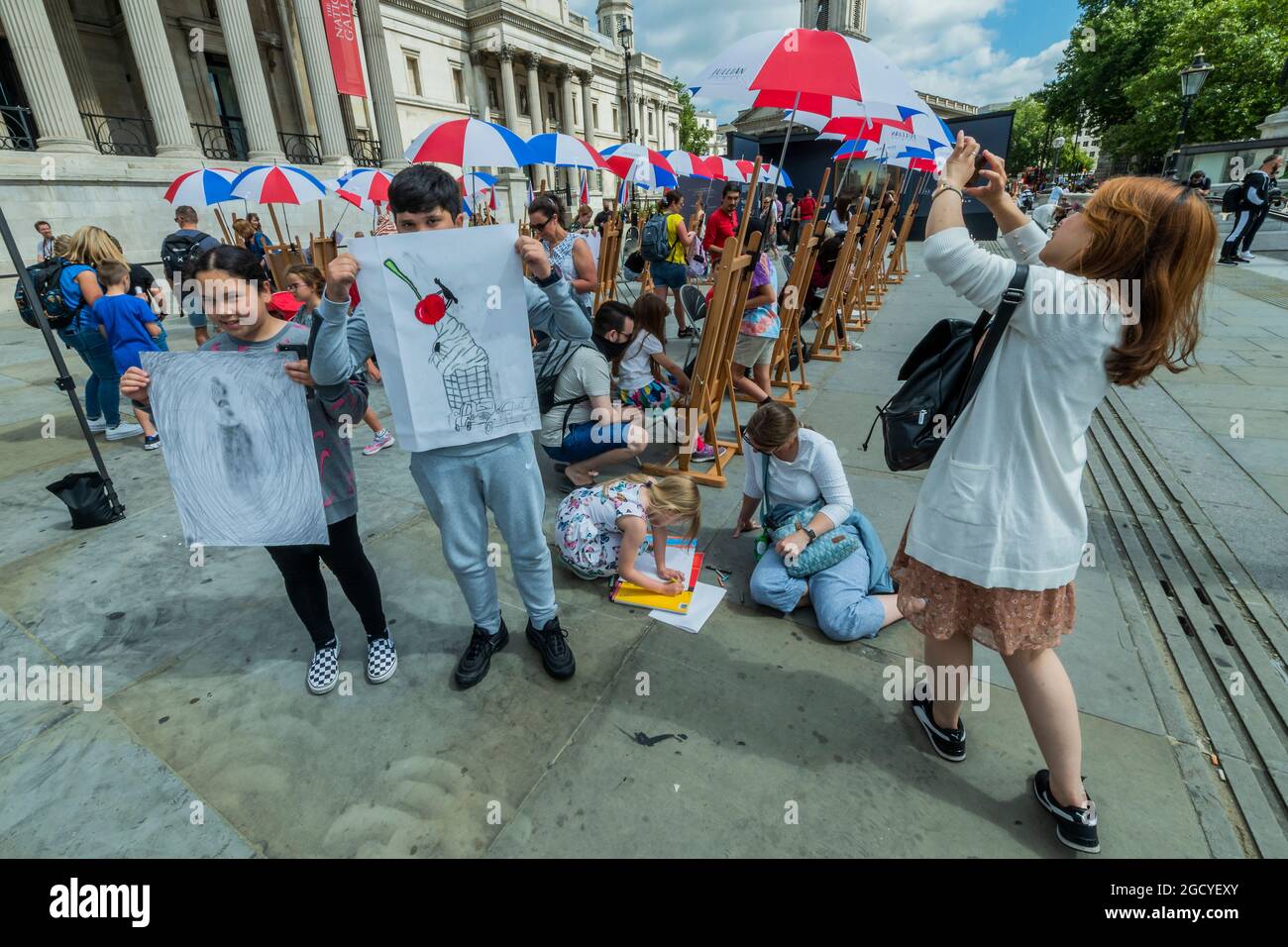 London, Großbritannien. August 2021. Ein paar Kinder zeigen ihre Werke - eine Pop-up-Galerie im Freien zeigt neben Sketch on the Square über 20 Reproduktionen beliebter Meisterwerke der National Gallery - und bringt Kunst im Rahmen des Inside Out Festivals, einem Monat kostenloser interaktiver Kunstveranstaltungen auf dem Trafalgar Square, in die freie Natur. Den ganzen August 2021 vor der Nationalgalerie, in Zusammenarbeit mit dem Stadtrat von Westminster. Kredit: Guy Bell/Alamy Live Nachrichten Stockfoto