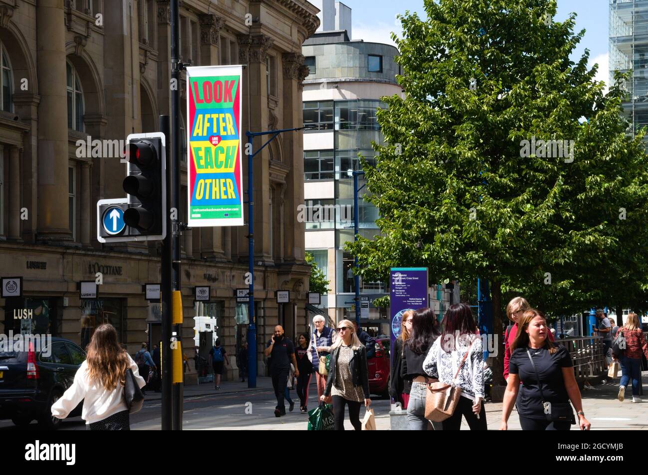 Manchester, Großbritannien, 10. August 2021. Die Menschen gehen an einem lokalen Schild vorbei, auf dem sie aufgefordert werden, sich in Manchester, Großbritannien, gegenseitig zu kümmern. Covid-19- oder Coronavirus-Infektionsraten sinken in Manchester, steigen aber in drei anderen Stadtteilen von Manchester an: Stockport, Bury und Trafford, laut den neuesten Daten von Public Health England. Quelle: Terry Waller/Alamy Live News Stockfoto