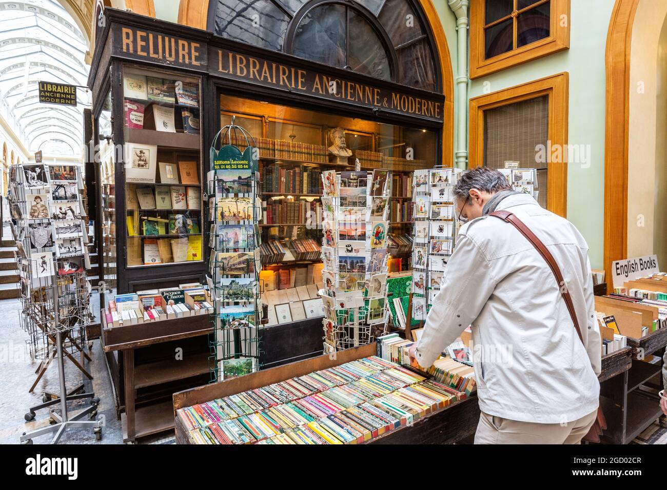 Jemand, der in einer Buchhandlung in der Galerie Vivienne in Paris Second-Hand-Bücher ansieht Stockfoto