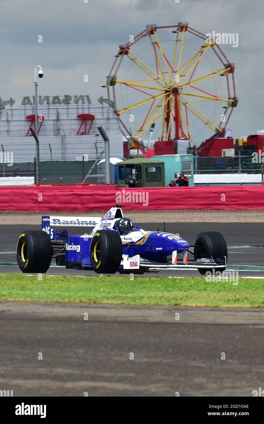 Damon Hill fährt den Williams FW18, in dem er 1996 die F1-Weltmeisterschaft gewann, durch den Loop mit dem großen Rad im Hintergrund. Stockfoto