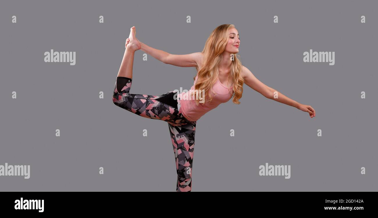 Eine junge Frau mit schönen blonden, langen Haaren (22 Jahre) in einer Reihe von Yoga- und Fitnessposen, die im Studio auf einem schlichten Hintergrund aufgenommen wurden. Stockfoto