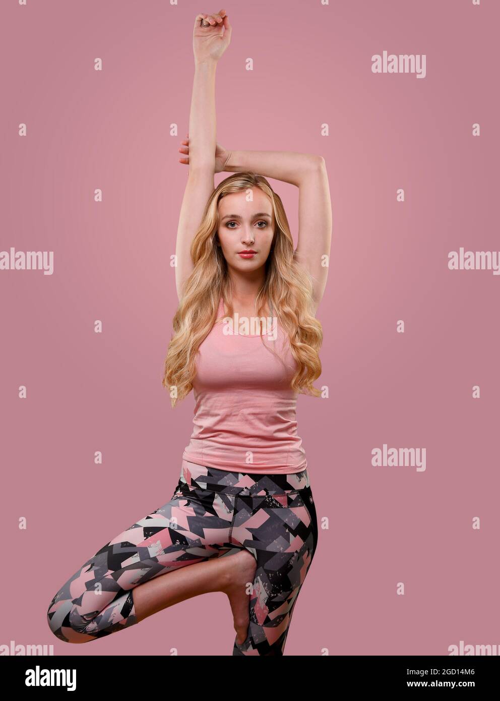 Eine junge Frau mit schönen blonden, langen Haaren (22 Jahre) in einer Reihe von Yoga- und Fitnessposen, die im Studio auf einem schlichten Hintergrund aufgenommen wurden. Stockfoto