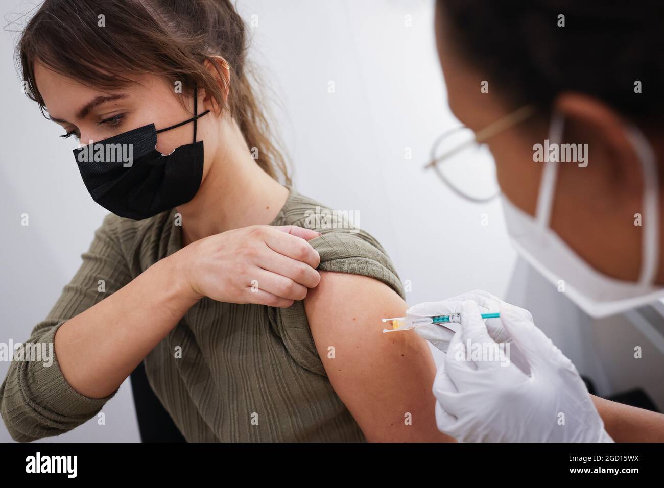 Hamburg, Deutschland. August 2021. Eine Frau erhält ihre zweite Impfung mit dem BioNTech/Pfizer-Impfstoff im Hamburger Impfzentrum in den Messehallen. Am letzten Tag der ersten Impfungen kam es erneut zu einem Ansturm im Hamburger Impfzentrum. Quelle: Christian Charisius/dpa/Alamy Live News Stockfoto