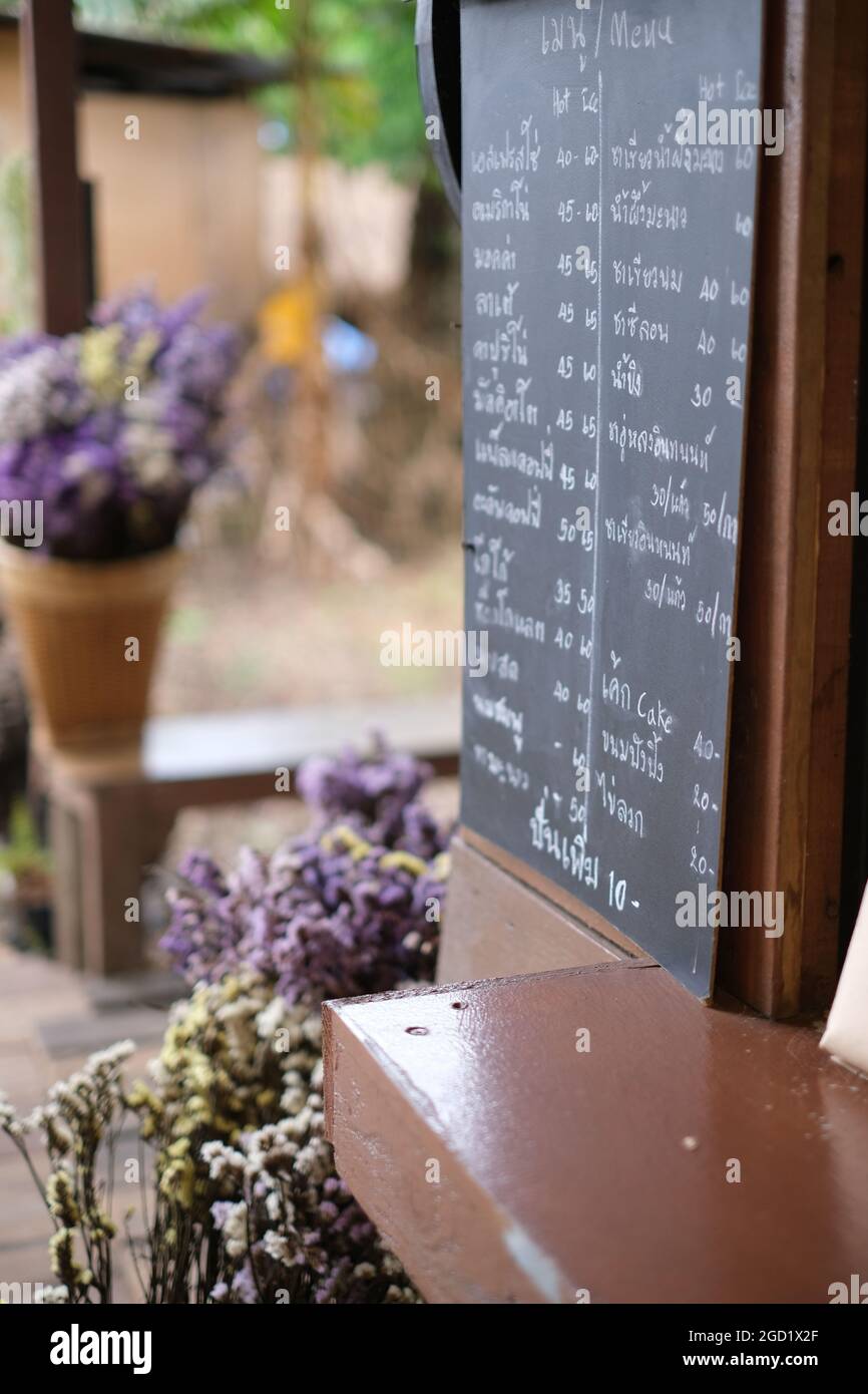 Ein Blumenstrauß aus getrockneten Blumen und eine Tafel mit dem heutigen Menü in einer Straßencafeteria in einem abgelegenen Dorf in Thailand Stockfoto