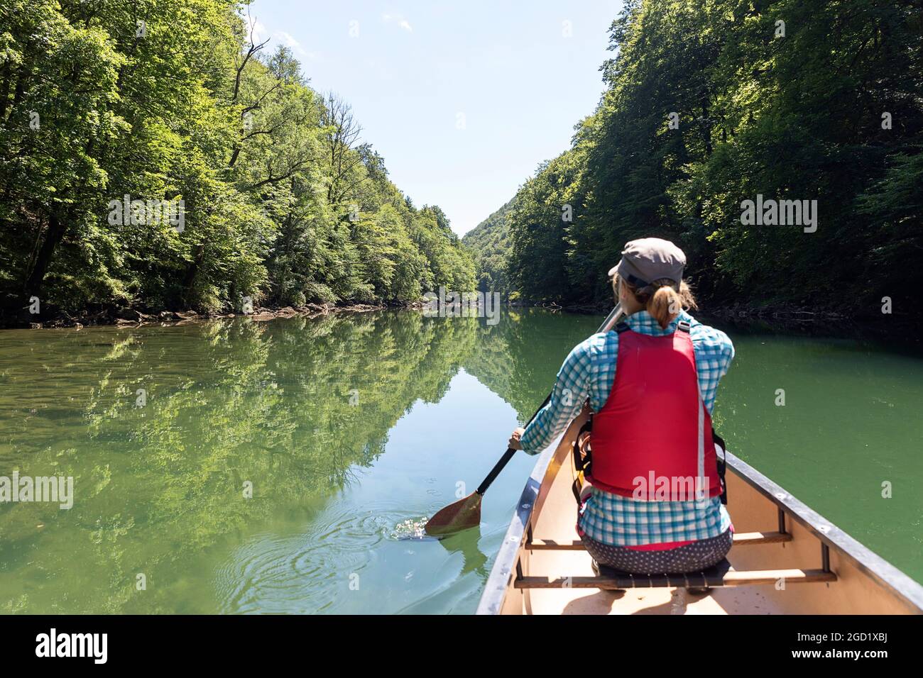 Frau mit Schwimmweste rudert im Kanu auf dem Fluss Kolpa, an der Grenze zwischen Slowenien und Kroatien Stockfoto