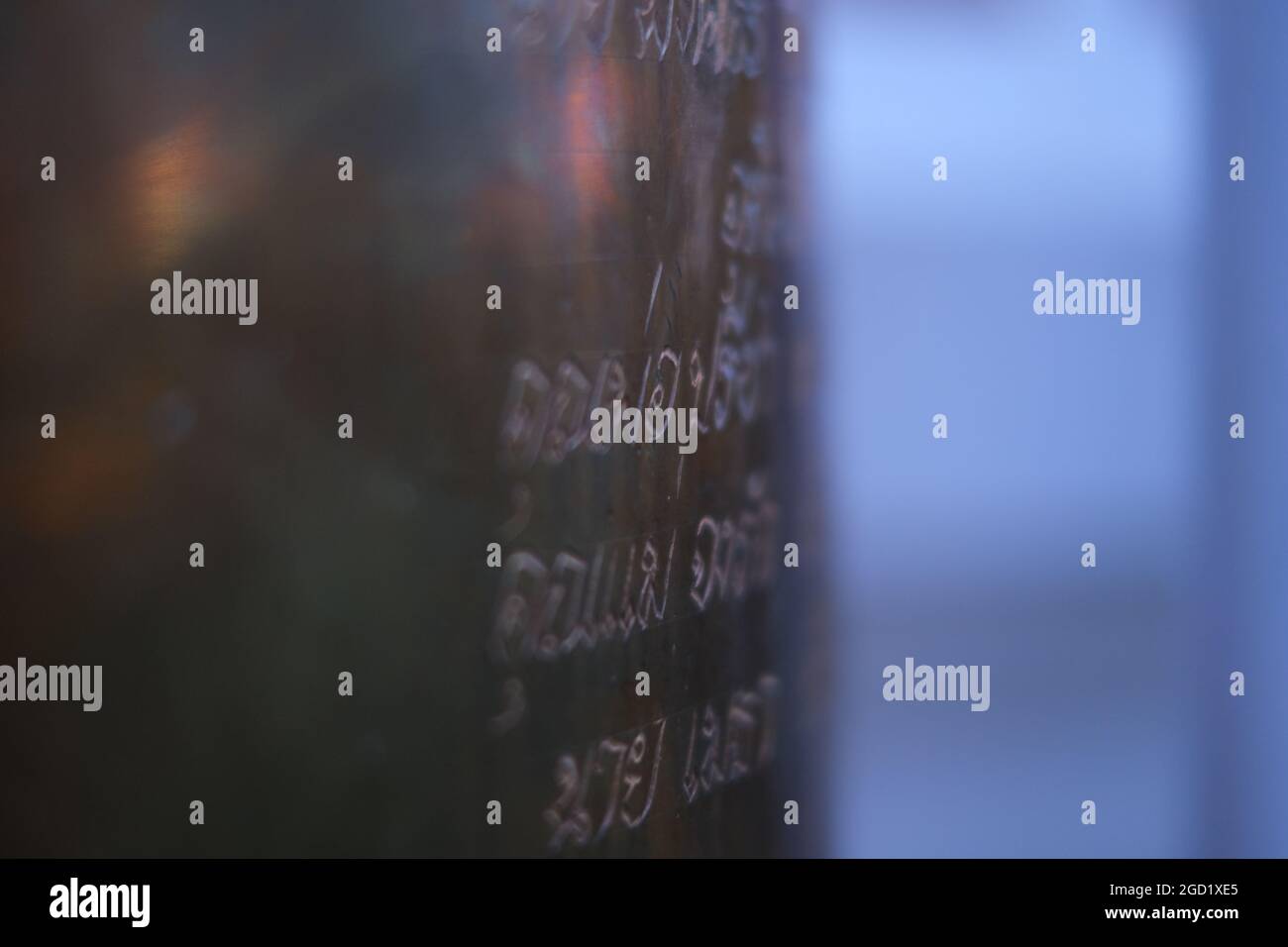 Traditionelle buddhistische Glocke - Ghanta - in der Dämmerung mit alten Inschriften und einem Glanz von Öllampen gesehen Stockfoto
