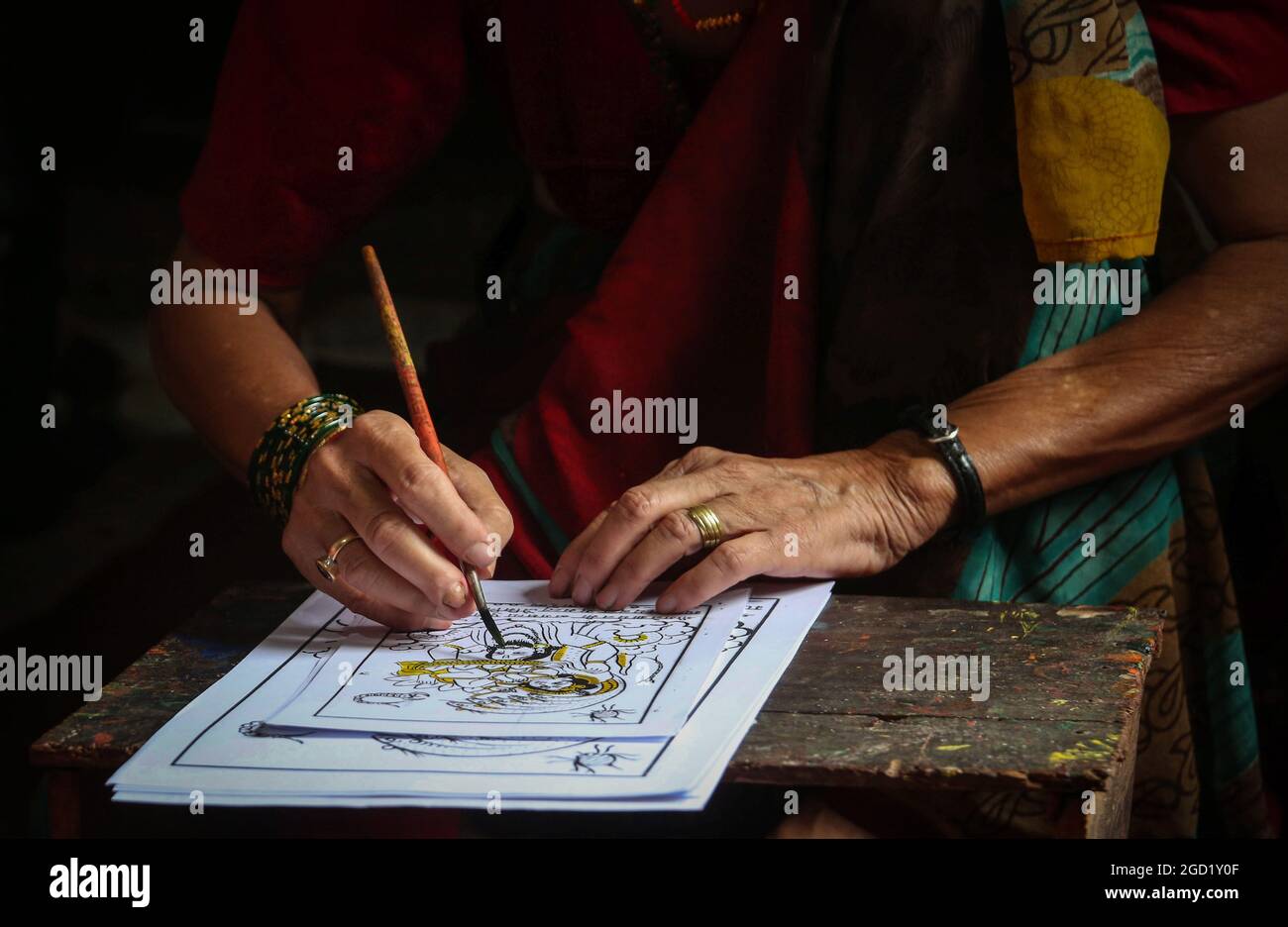 Bhaktapur, Bagmati, Nepal. August 2021. Chet Kumari Chitrakar, 68, populär bekannt als ''Schöpfer der Götter'', gibt dem traditionellen Image den letzten Schliff für das bevorstehende Nag Panchami Festival, ein hinduistisches Festival für die Anbetung der Schlangengottheit in Bhaktapur, einer Stadt, die auch als ''˜die Stadt der Devotees' in Nepal am 10. August 2021 bekannt ist. Chet Kumari Chitrakar und seine Familie machen weiterhin solche Handdruckbilder für viele Festivals, trotz der geringeren Nachfrage aufgrund des Interesses der Menschen an den modernen Maschinendruckbildern. Chitrakar Familien sind im Grunde als Maler und Bildhauer in Nepal bekannt, die Götter und g dargestellt Stockfoto