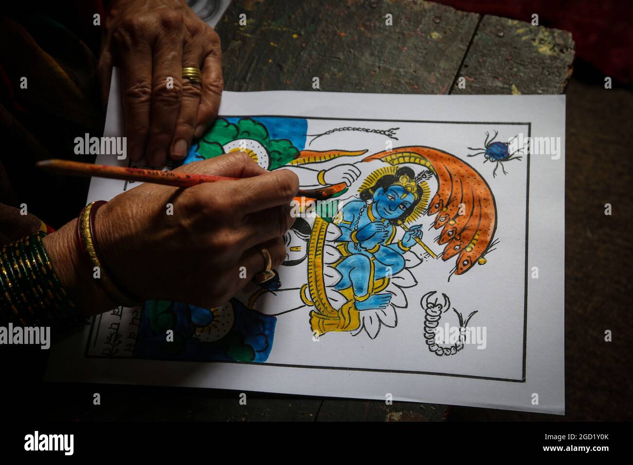Bhaktapur, Bagmati, Nepal. August 2021. Chet Kumari Chitrakar, 68, populär bekannt als ''Schöpfer der Götter'', gibt dem traditionellen Image den letzten Schliff für das bevorstehende Nag Panchami Festival, ein hinduistisches Festival für die Anbetung der Schlangengottheit in Bhaktapur, einer Stadt, die auch als ''˜die Stadt der Devotees' in Nepal am 10. August 2021 bekannt ist. Chet Kumari Chitrakar und seine Familie machen weiterhin solche Handdruckbilder für viele Festivals, trotz der geringeren Nachfrage aufgrund des Interesses der Menschen an den modernen Maschinendruckbildern. Chitrakar Familien sind im Grunde als Maler und Bildhauer in Nepal bekannt, die Götter und g dargestellt Stockfoto