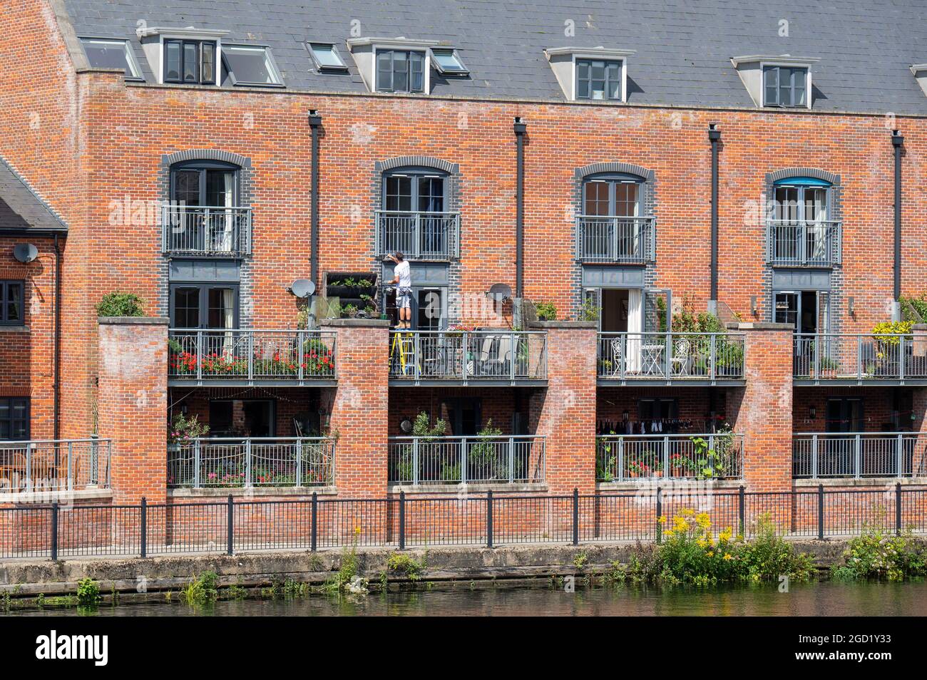 Ein Blick auf die neu erbauten Wohnungen am Riverside mit einem Mann auf Treppen, der die Metallgeländer bemalt Stockfoto