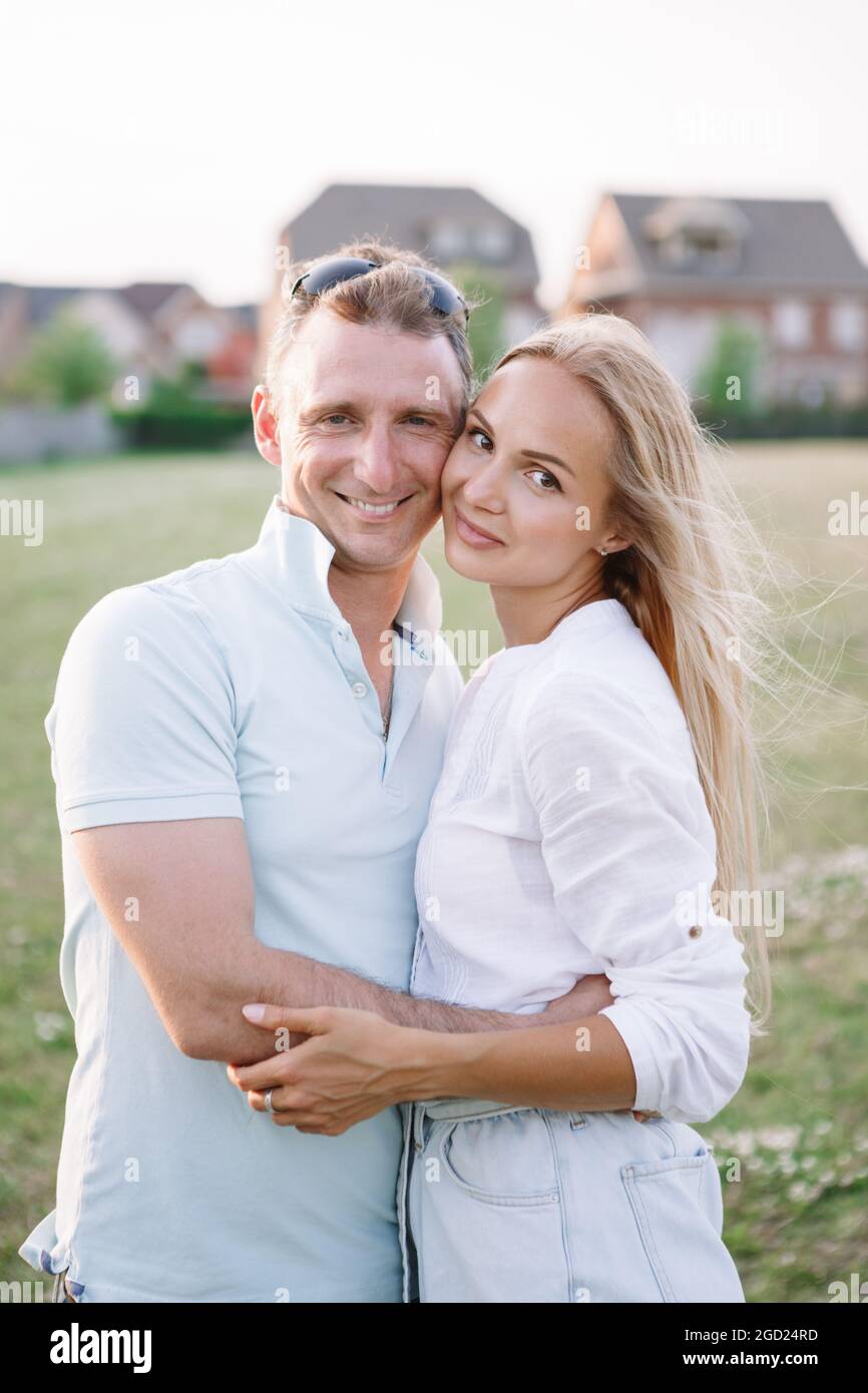 Kaukasischer Mann und junge Frau mittleren Alters umarmen sich im Park im Freien. Glücklich romantisches Paar in der Liebe aus zusammen. Glücklich verheiratet Mann und Frau Stockfoto