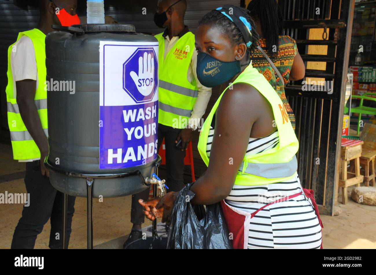 Eine Frau, die sich die Hände wusch, bevor sie in ein Geschäft eintrat. Die Regierung hat Gesundheitsrichtlinien zur Bekämpfung von Covid-19 ausgearbeitet. Uganda. Stockfoto