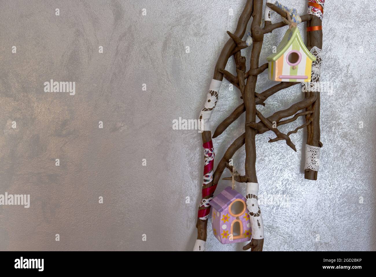 Eine Installation mit trockenen Ästen und Vogelhaus auf silbernem Hintergrund Stockfoto