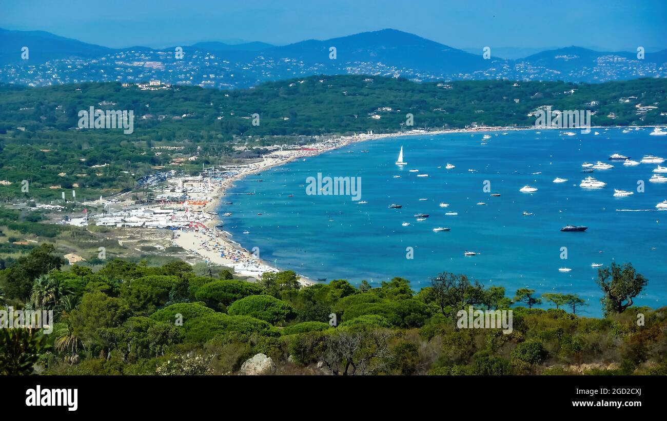 Panoramablick auf die mediterrane Meeresbucht mit Booten vor blauem Sommerhimmel und Bergen im Hintergrund - Plage de pampelonne, St. Tropez (Fokus auf Lower Thi Stockfoto