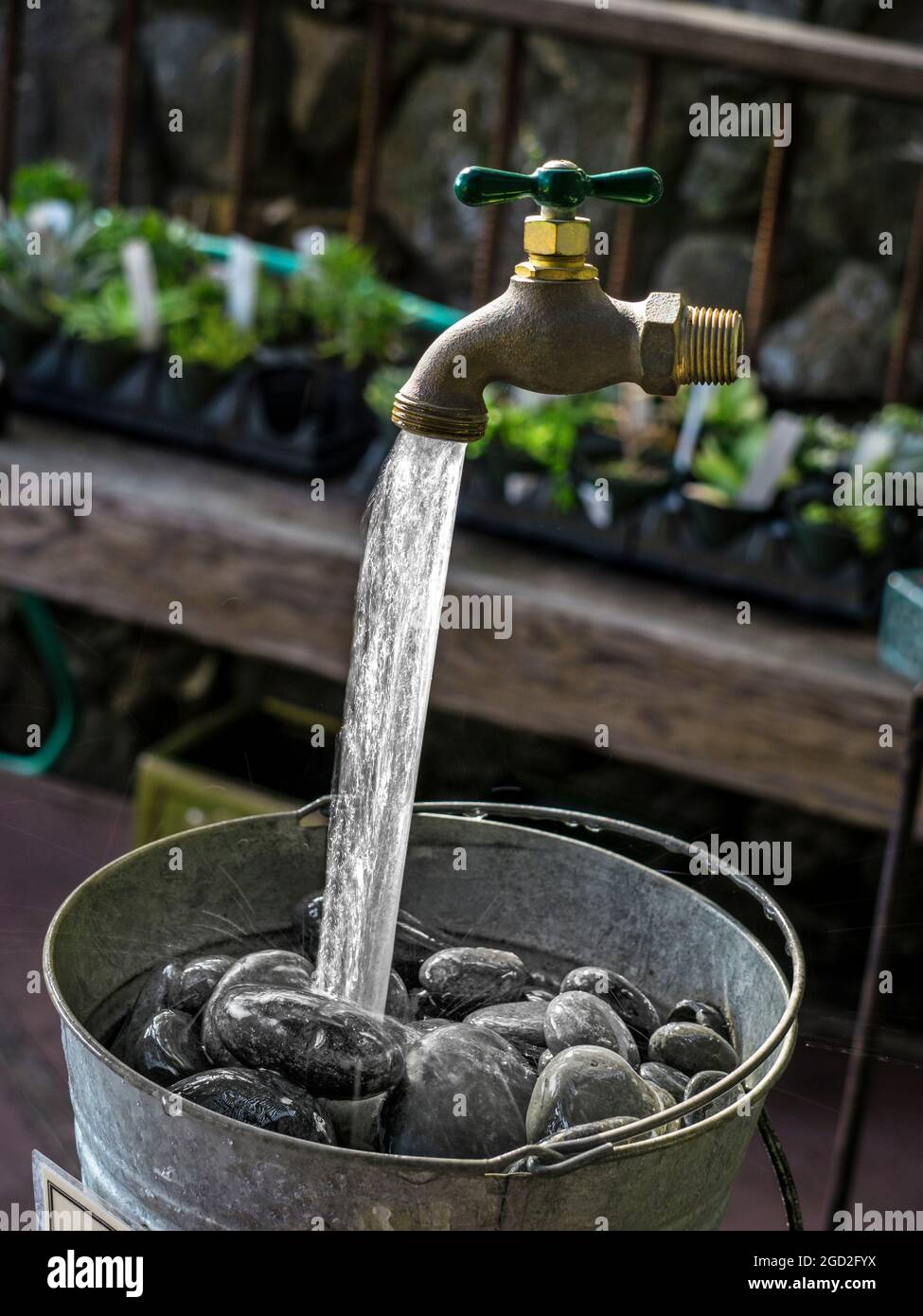 Magic Garden Tap-Funktion Wasser läuft scheinbar Neuheit Trick, Wasser läuft in Stein gefüllten Wassereimer aus Wasserhahn scheinen in der Luft zu schweben Stockfoto