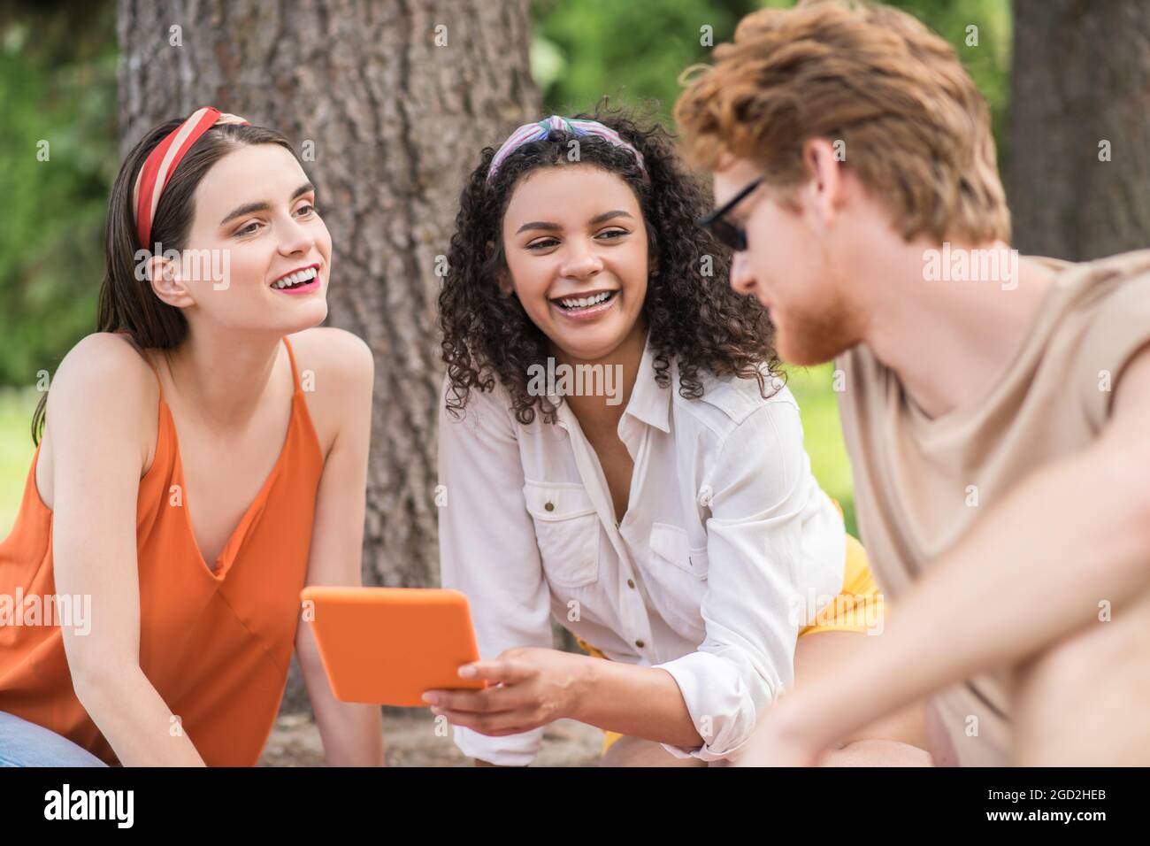 Typen und Mädchen mit Tablet kommunizieren beim Picknick Stockfoto