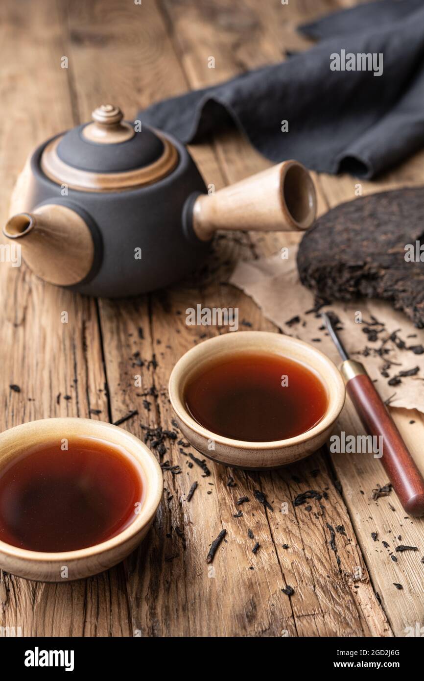 Medizinischer Pu-erh-Tee in Keramikbechern auf Holzhintergrund Stockfoto