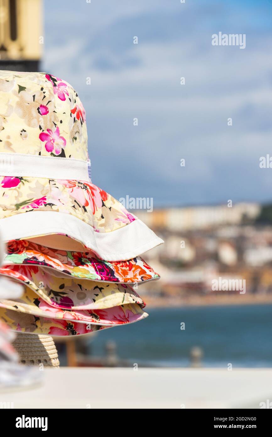 Bunte blumige Stoff Strand Sonnenhüte in Scarborough Yorkshire mit verschwommenem Hintergrund Stockfoto