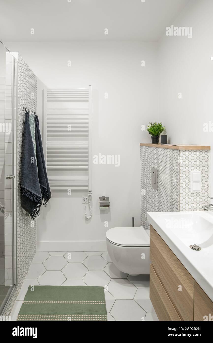 Moderne, minimalistische Einrichtung im Badezimmer mit weißen Fliesen, zwei  weißen Waschbecken und Naturholzmöbeln Stockfotografie - Alamy