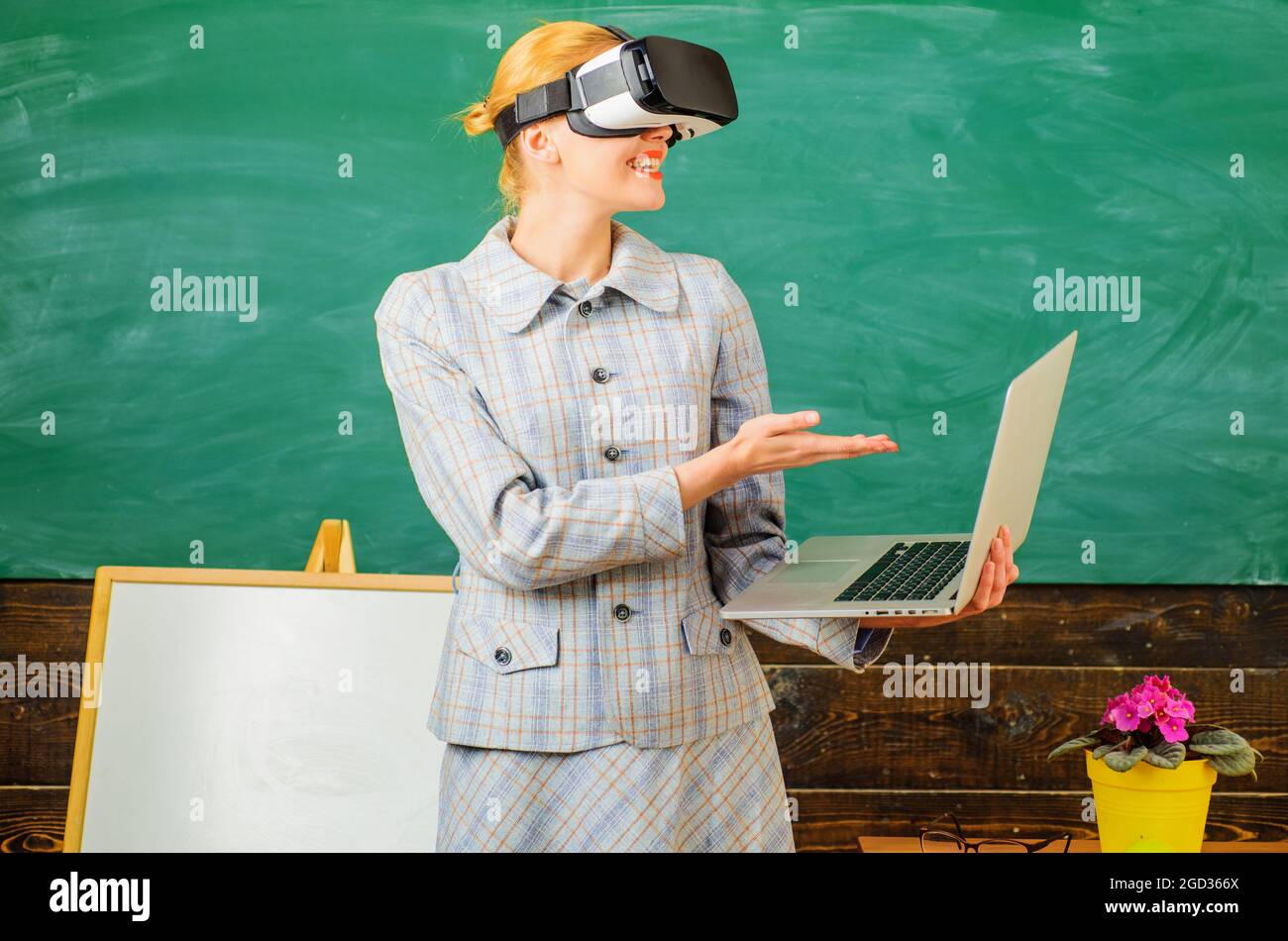 Lehrer mit Laptop in vr-Headset. Moderne Technologien in der intelligenten Schule. Digitale Bildung. Lächelnder Tutor im Klassenzimmer. Stockfoto