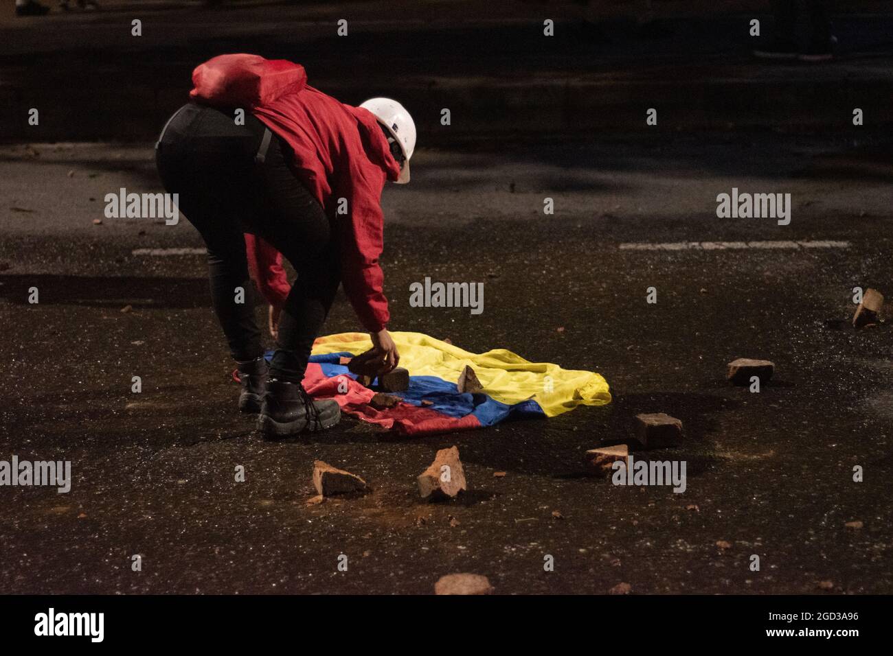 Bogota, Kolumbien, 09/08/2021, EIN Demonstrator pflückt während der Anti-Regierung-Proteste Felsen aus einer kolumbianischen Flagge, die in Zusammenstößen zwischen Demonstranten und der kolumbianischen Bereitschaftspolizei (ESMAD) endete, während die Demonstranten, die während der letzten 3 Monate regierungsfeindlicher Proteste im Norden Bogotas, Kolumbien, in den Tibabuyes lagerten, vertrieben wurden Stockfoto