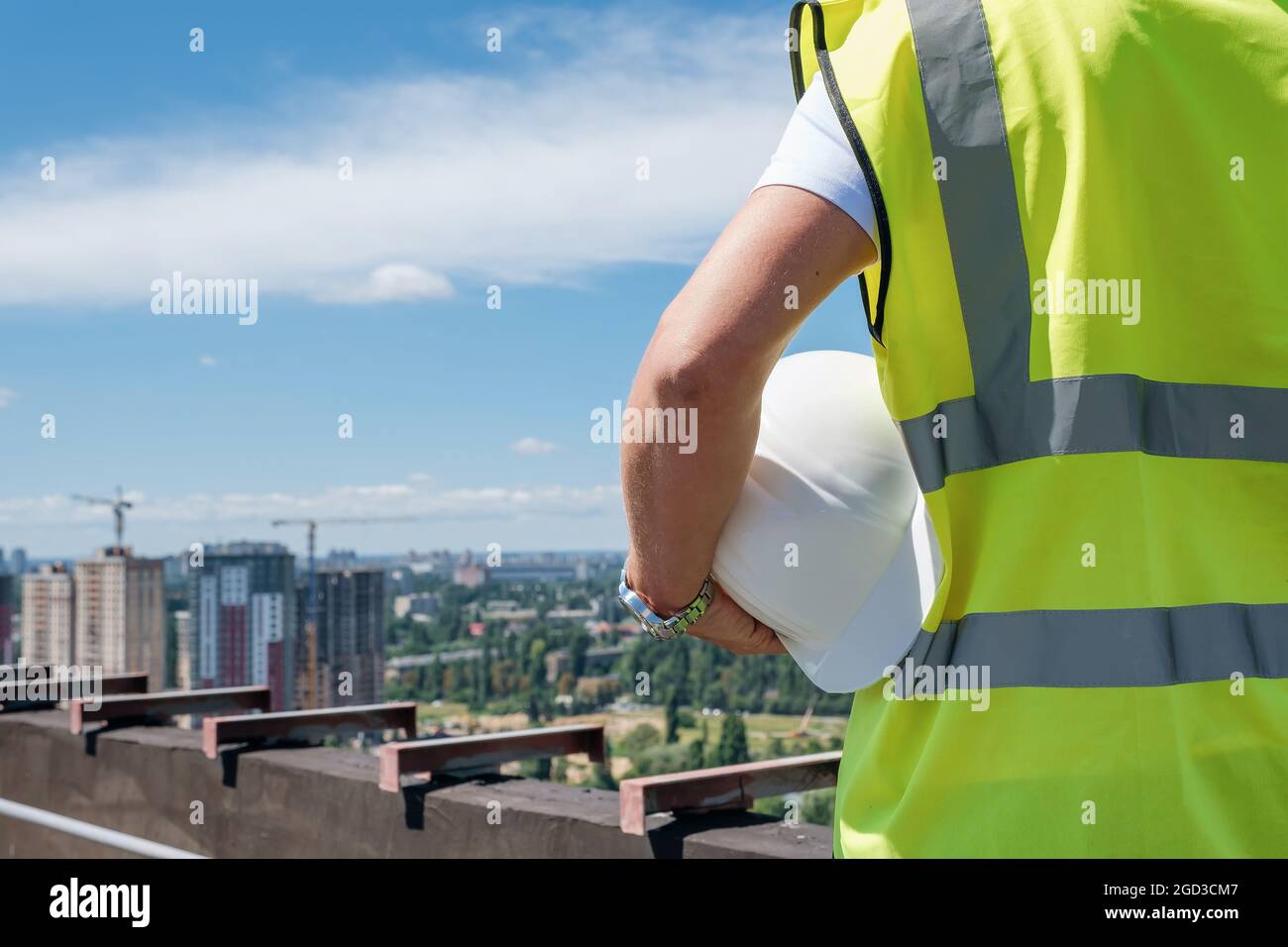 Der Mann hält weißen Hut in der Hand auf dem Dach des Gebäudes im Bau Stockfoto
