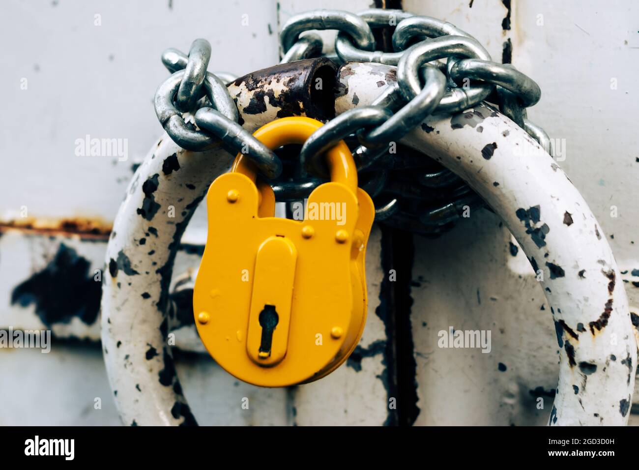 Altes, verschlossenes Vorhängeschloss hängt an der Kette. Schlechtes Sicherheitskonzept. Veraltete Sicherheitstechnologie Stockfoto