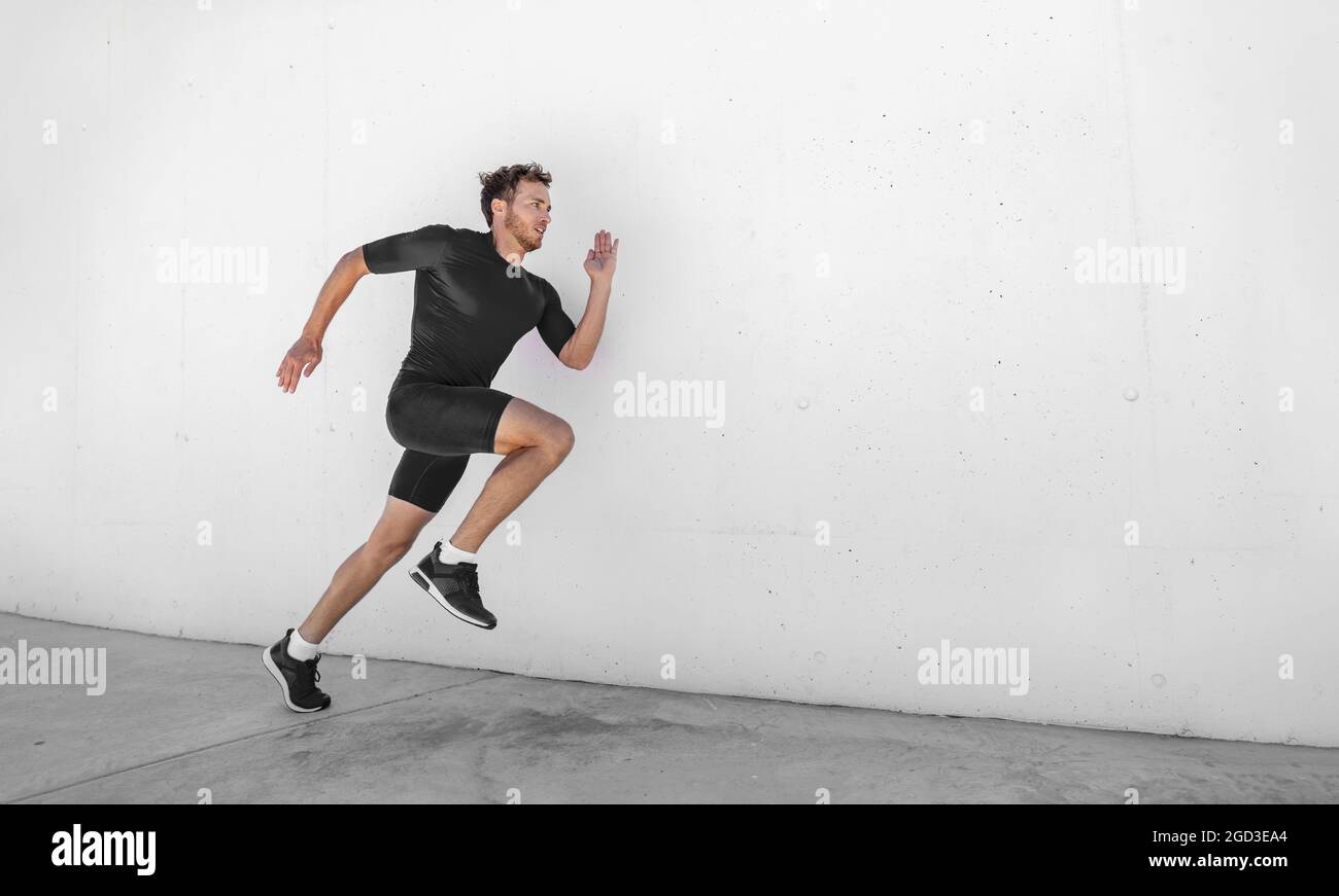 Sportlertraining schnelles Laufen mit explosivem Sprint für den Wettkampf. Mann Läufer beim Training im Fitness-Studio draußen weißen Wand Hintergrund. Stockfoto