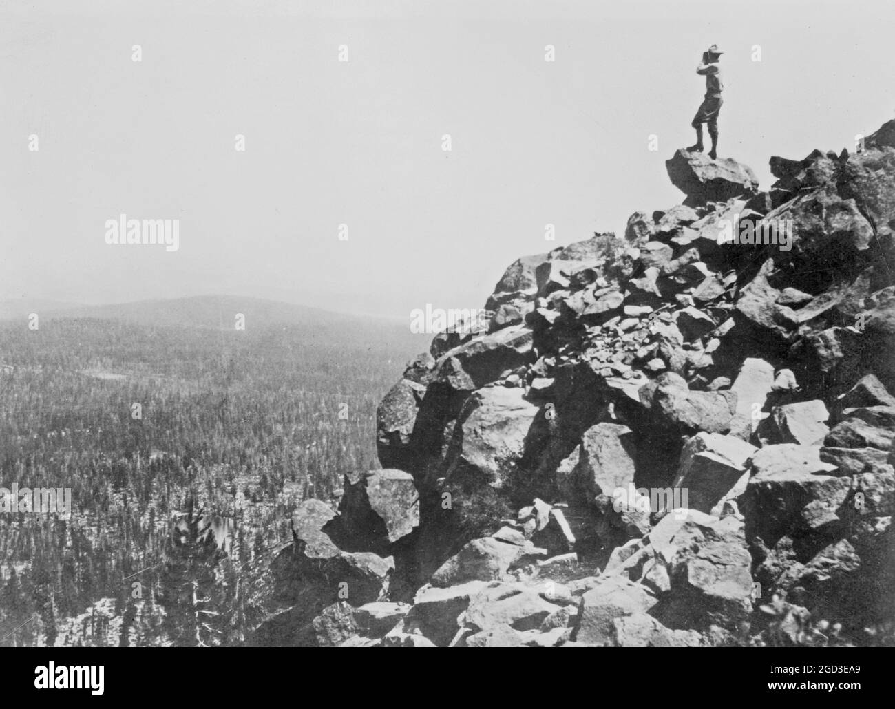 Mann, der von einer felsigen Klippe in einen nicht identifizierten Nationalpark blickt. 1909 Stockfoto