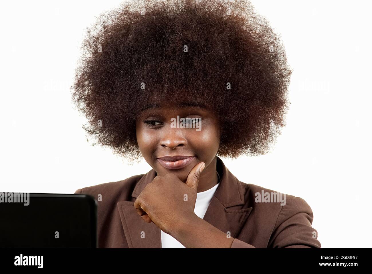 Junge schwarze Geschäftsführerin aus Lateinamerika, mit afro-Haaren, mit interessierenden Gesten, die auf einen Laptop blicken, auf weißem Hintergrund Stockfoto