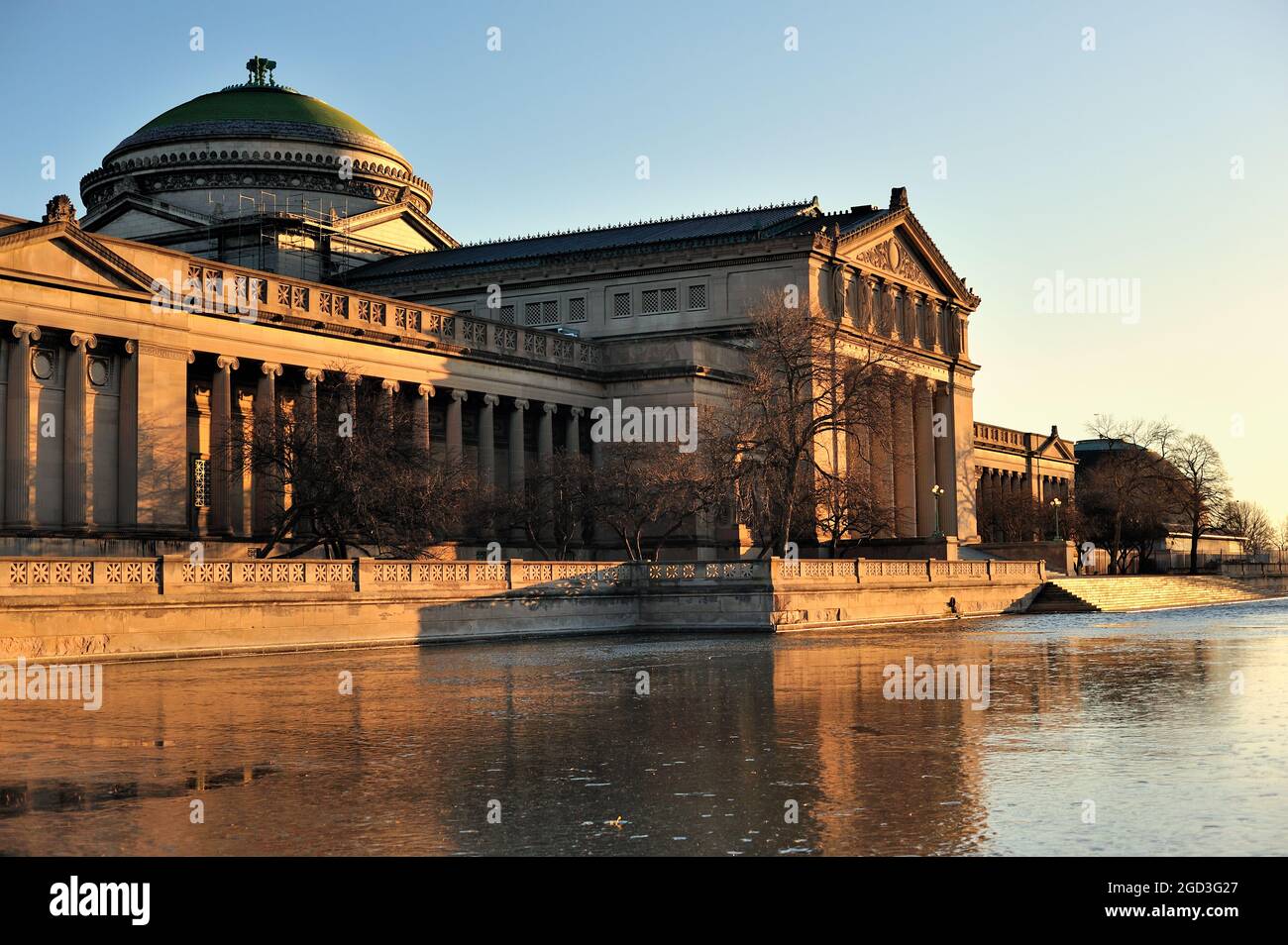 Chicago, Illinois, USA. Das Museum für Wissenschaft und Industrie spiegelt sich in einem noch gefrorenen Teich kurz nach Sonnenaufgang. Stockfoto