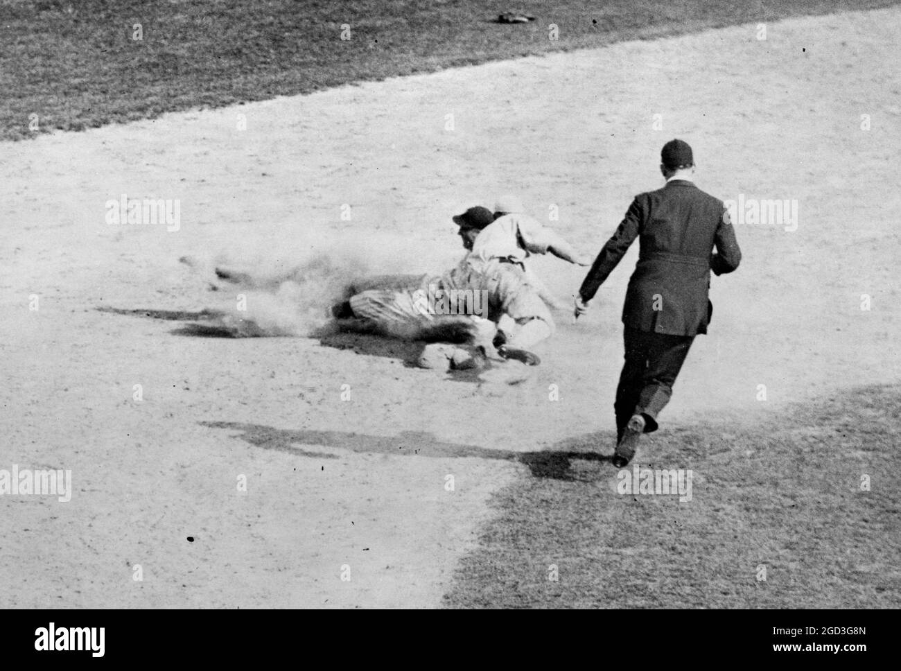 Schiedsrichter läuft, um einen Mann anzurufen, der während des Baseballspiels zwischen 1910 und 1930 in die zweite Basis rutscht Stockfoto
