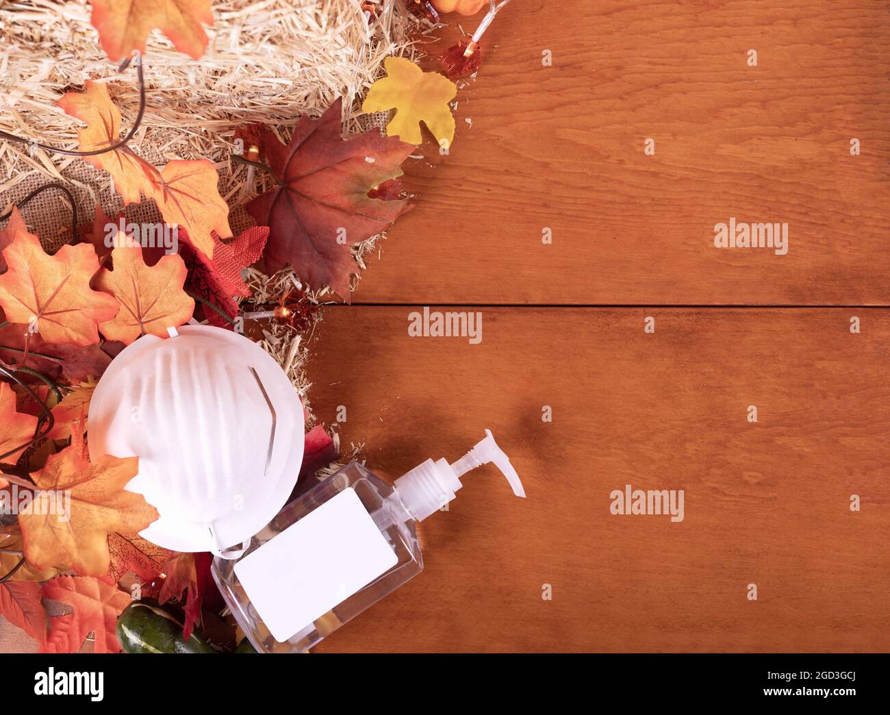 Happy Thanksgiving Day mit Gesichtsmaske und Händedesinfektionsmittel, Ahornblättern und Kürbis auf Holzhintergrund. Herbstkomposition mit Kopierraum. Draufsicht. Stockfoto