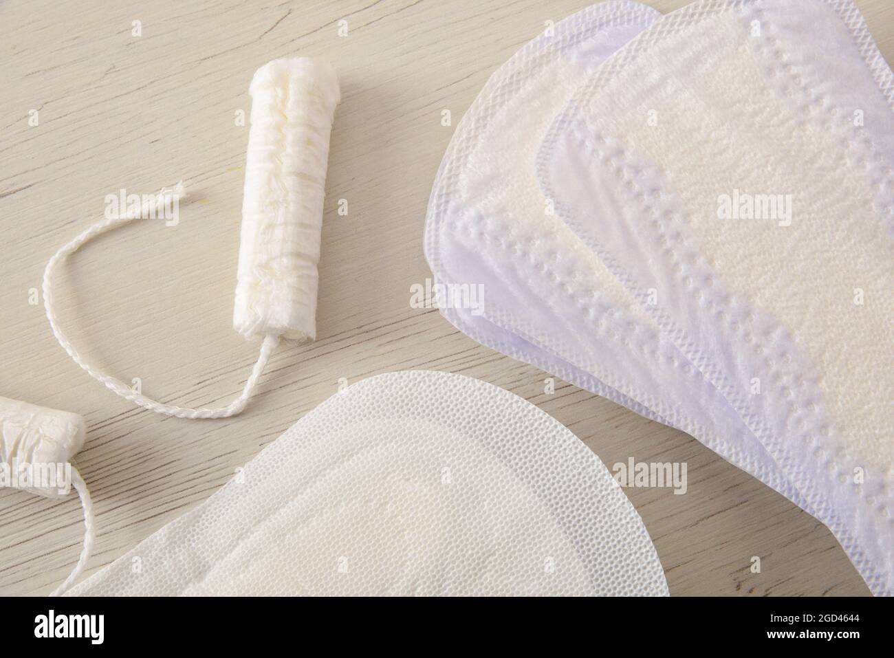 Hintergrund mit weiblichen absorbierenden Protektoren für den Menstruationszyklus. Pantiliner, Serviette und Tampon auf weißem Holztisch. Draufsicht. Horizontal komposit Stockfoto