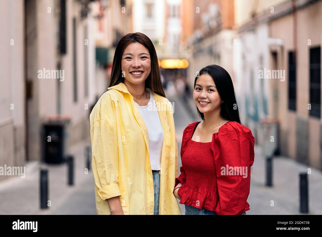 Glückliche junge asiatische Freundinnen, die lächeln und in der Stadt Madrid die Kamera betrachten. Stockfoto