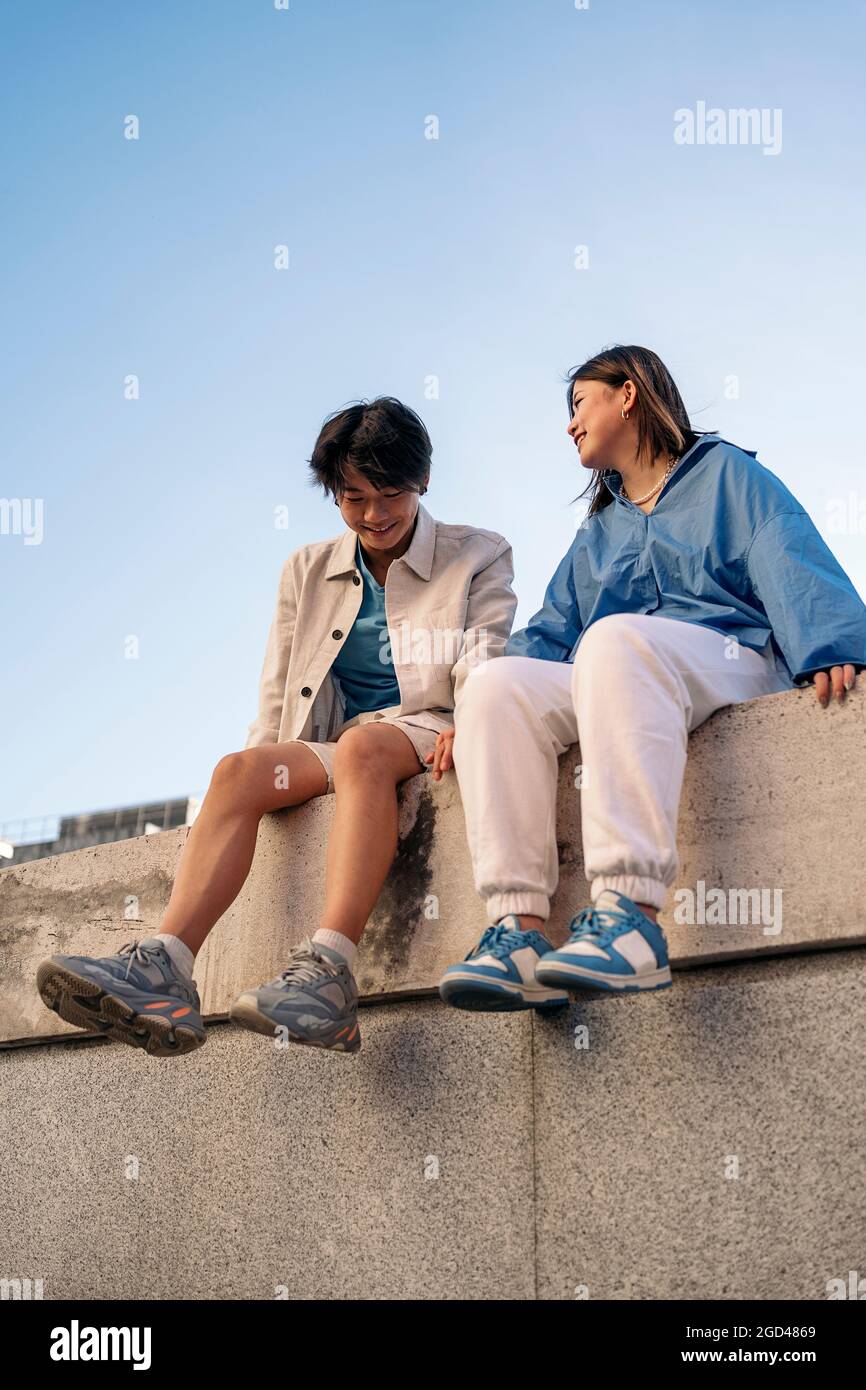 Cooles und junges asiatisches Paar, das in der Stadt sitzt, Spaß hat und sich anschaut. Stockfoto