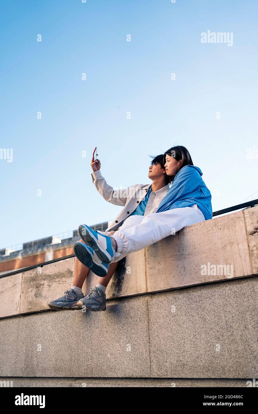Cooles und junges asiatisches Paar, das in der Stadt posiert und Selfie mit dem Telefon nimmt. Stockfoto