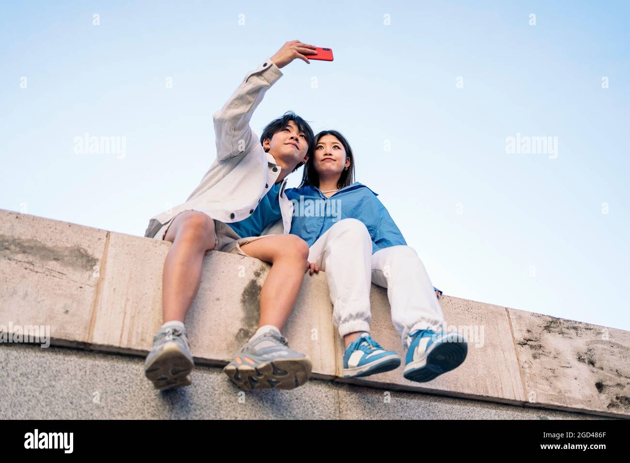 Glückliches junges asiatisches Paar, das in der Stadt posiert und Selfie mit ihrem Telefon macht. Stockfoto