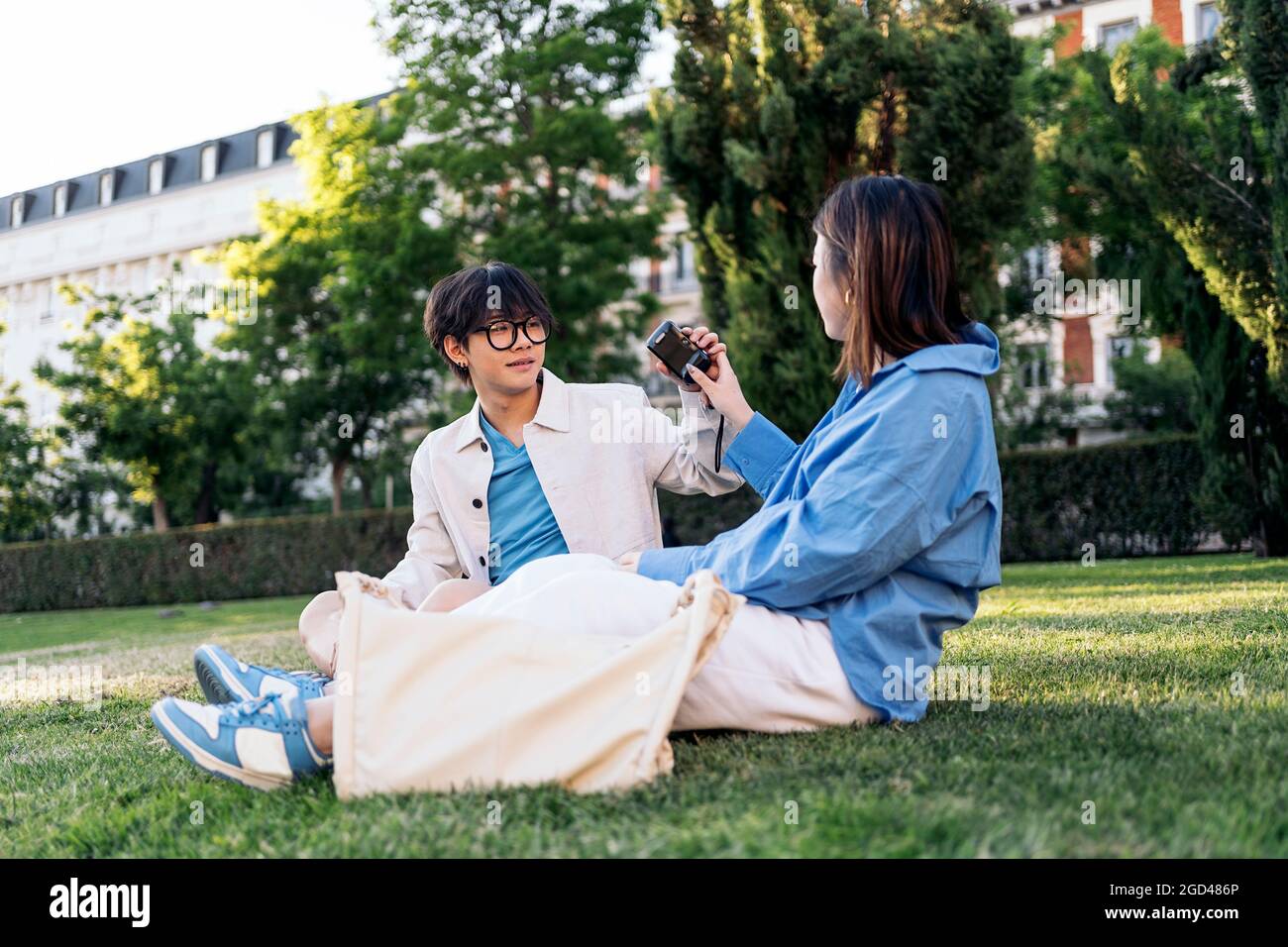 Unbekannte Frau, die im Park Fotos mit ihrem asiatischen Freund macht. Stockfoto