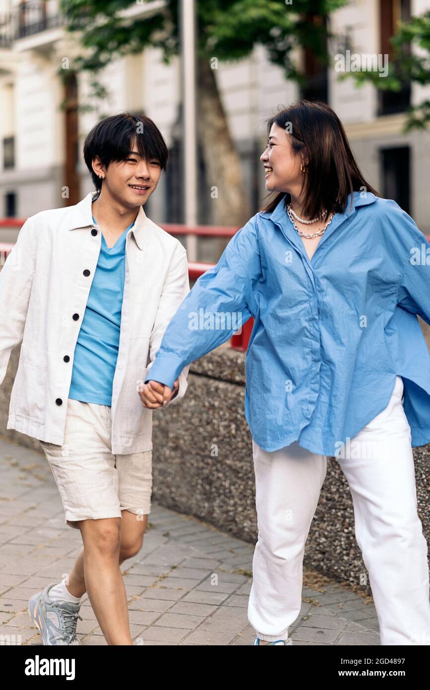 Glückliches asiatisches Paar, das an sonnigen Tagen in der Stadt herumläuft und die Hände hält. Stockfoto