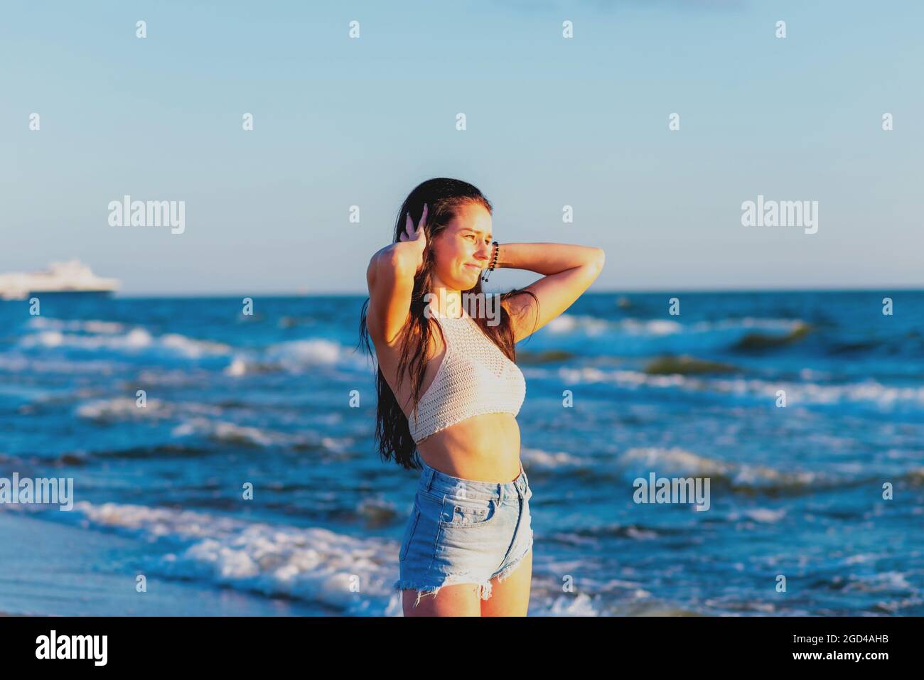 Junge Frau, die im Sommer im Meer spielt. Frau, die im Meerwasser genießt. Fröhliche junge Frau, die Spaß am Strand hat. Sie ist entspannt im Meerwasser und Stockfoto