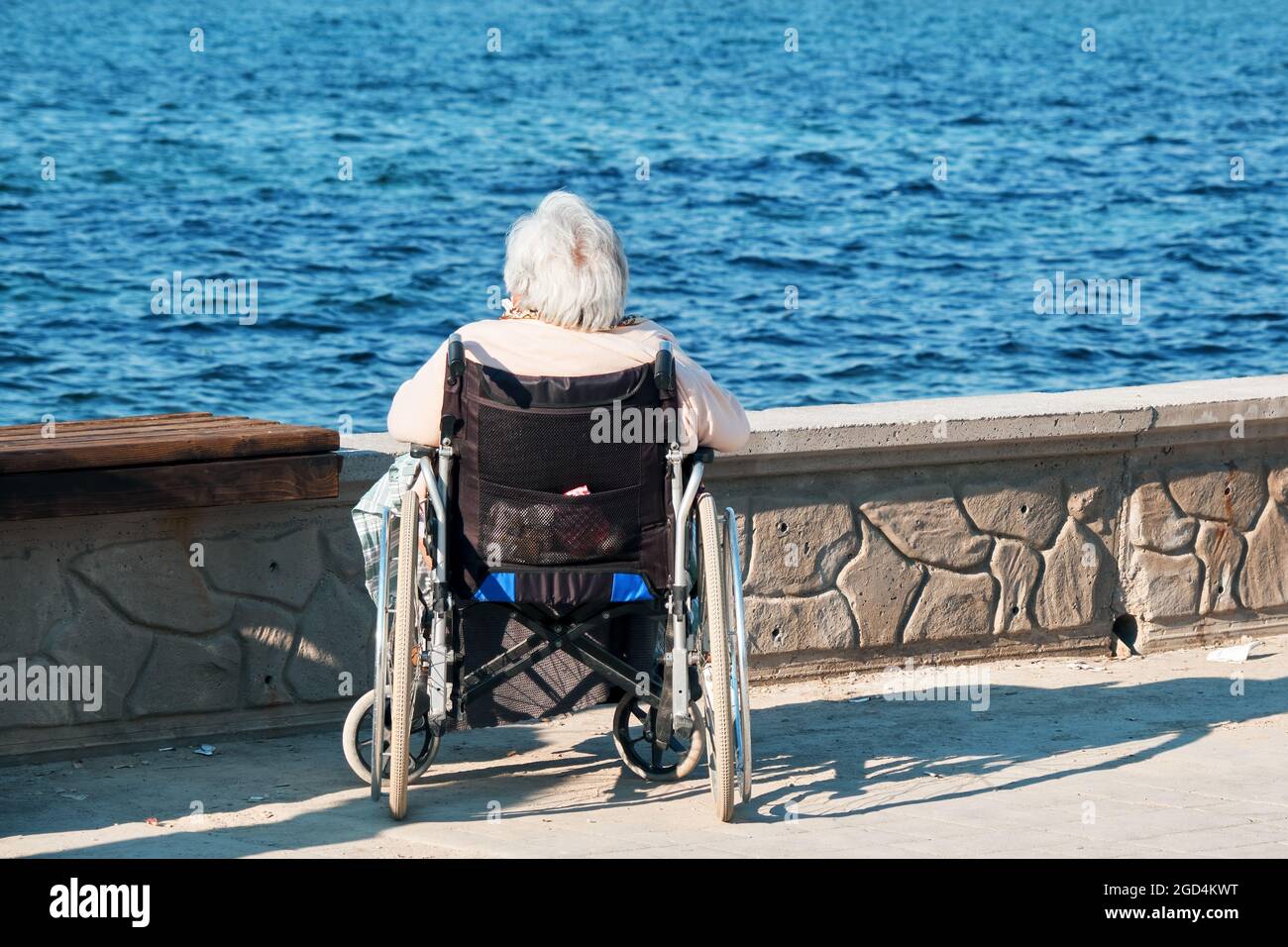 Einsame ältere ältere Frau im Rollstuhl beobachtet das Meer in der Nähe des Meeres. Stockfoto