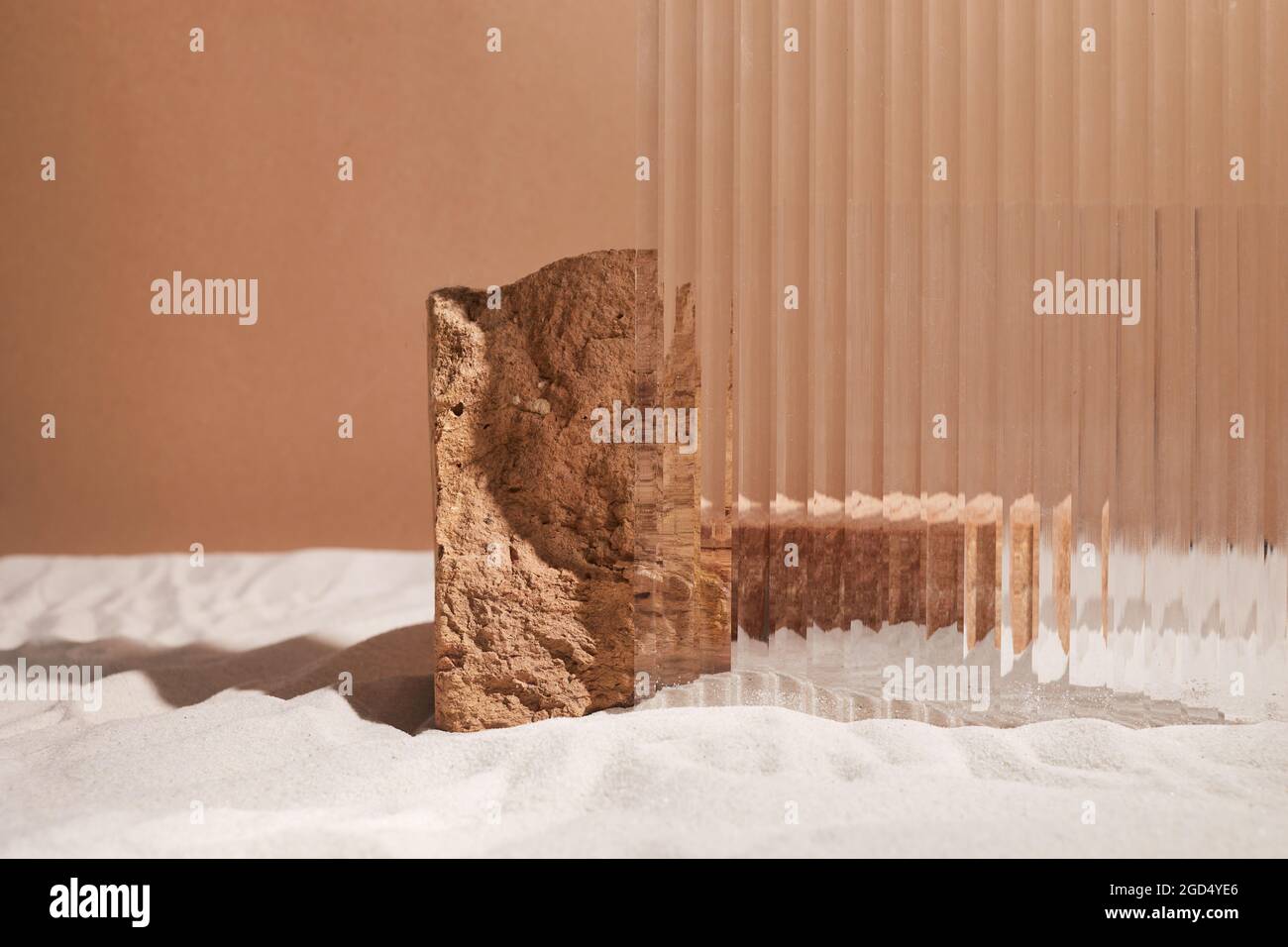 Podestständer und texturiertes Glas auf Sandhintergrund. Display für kosmetische Parfüm Mode Naturprodukt Stockfoto